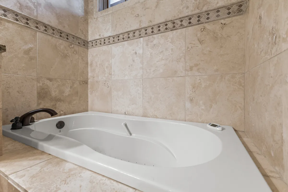 A stylish bathroom with a luxurious soaking tub, elegant tile trim, and a sleek faucet. The serene, spa-inspired design invites moments of relaxation and self-care after a day of adventure.